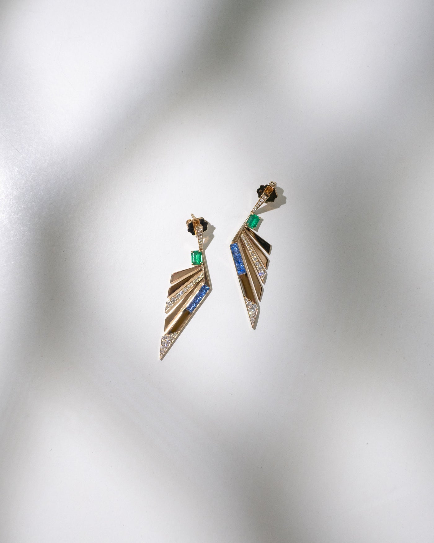 Pair of decorative gemstone gold earrings on a textured gray background