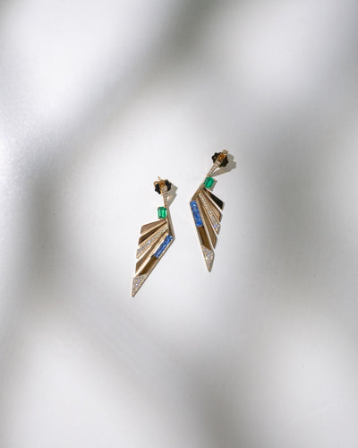 Pair of decorative gemstone gold earrings on a textured gray background